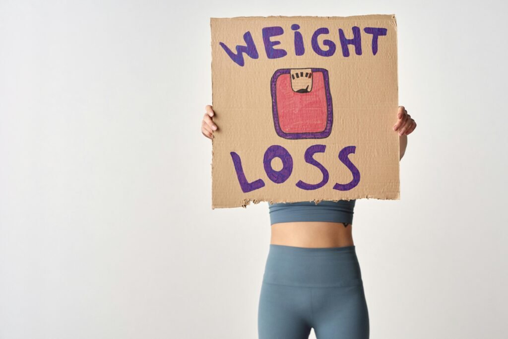 Home Person holding 'weight loss' sign for fitness motivation and health goals.